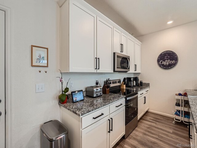 17991 E 103rd Ave, Commerce City, CO 80022 - kitchen featuring stainless steel appliances, baseboards, dark stone countertops, white cabinetry, and wood finished floors