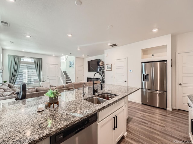 17991 E 103rd Ave, Commerce City, CO 80022 - kitchen featuring stainless steel appliances, a sink, open floor plan, wood finished floors, and white cabinets