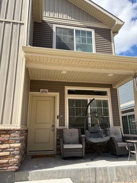 17991 E 103rd Ave, Commerce City, CO 80022 - entrance to property featuring stone siding, a porch, and board and batten siding