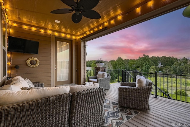 deck at dusk featuring outdoor lounge area and ceiling fan