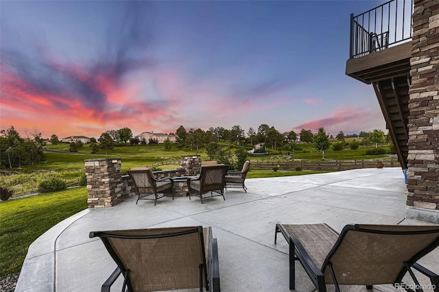 patio terrace at dusk with a balcony and a yard