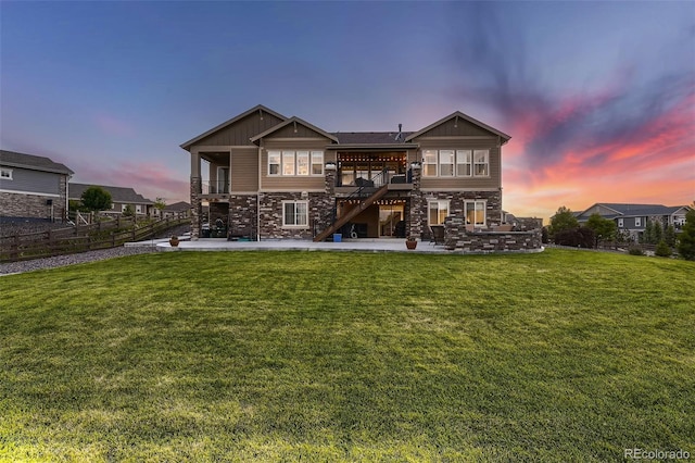 back house at dusk featuring a lawn, a patio, and a wooden deck