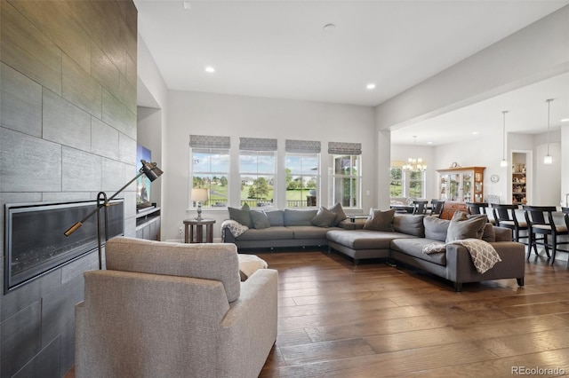 living room featuring dark hardwood / wood-style flooring, a tiled fireplace, and a chandelier