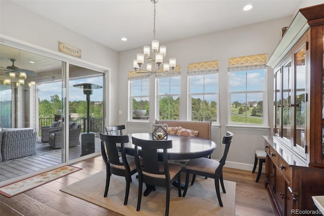 dining room featuring ceiling fan with notable chandelier and light hardwood / wood-style floors