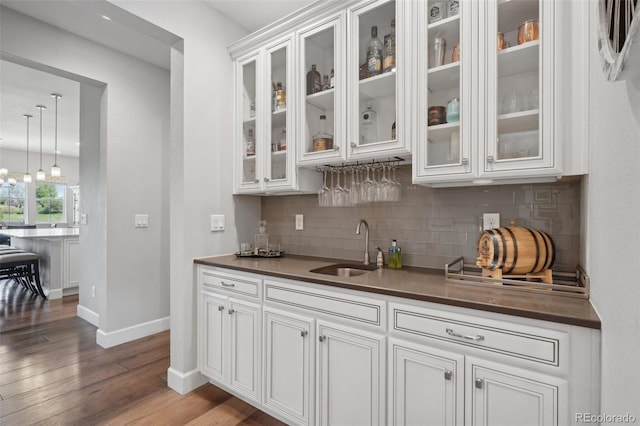 bar with white cabinetry, sink, decorative light fixtures, decorative backsplash, and hardwood / wood-style flooring