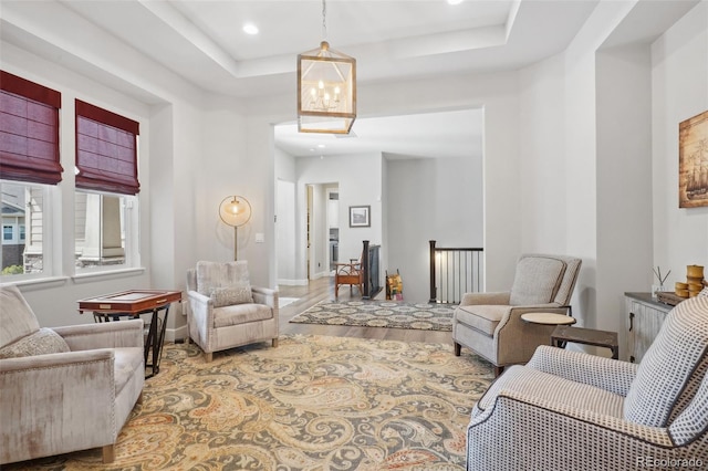 living room featuring hardwood / wood-style floors, a tray ceiling, and a notable chandelier