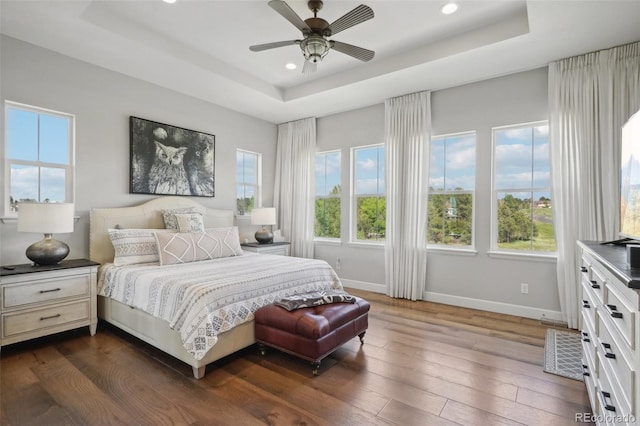 bedroom with a raised ceiling, ceiling fan, and dark wood-type flooring