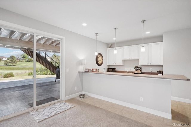 kitchen featuring kitchen peninsula, white cabinetry, light tile patterned floors, and decorative light fixtures