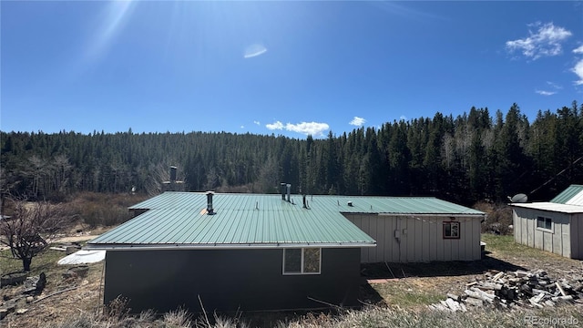 view of property exterior with metal roof and a forest view