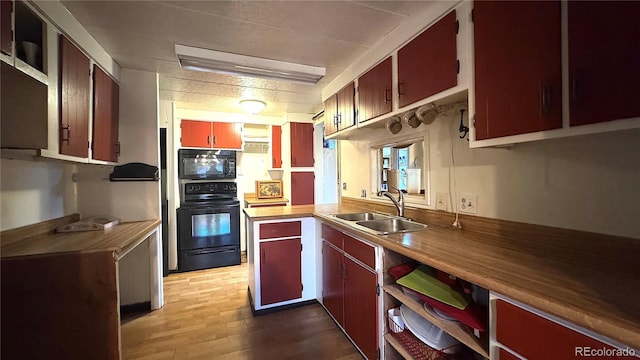 kitchen featuring a sink, wood finished floors, and black appliances