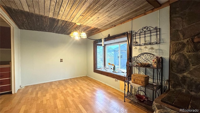unfurnished living room with wood ceiling, baseboards, an inviting chandelier, and wood finished floors