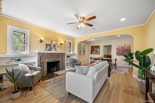 1601 Albion St, Denver, CO 80220 - living area featuring crown molding, arched walkways, ceiling fan, a brick fireplace, and wood finished floors
