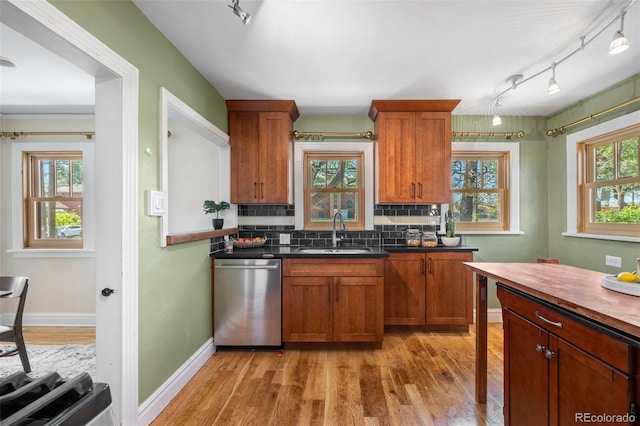 1601 Albion St, Denver, CO 80220 - kitchen featuring dishwasher, a sink, light wood-style floors, tasteful backsplash, and brown cabinets