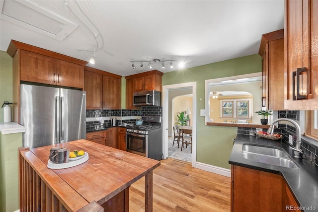 1601 Albion St, Denver, CO 80220 - kitchen featuring appliances with stainless steel finishes, a sink, light wood-style floors, brown cabinets, and tasteful backsplash
