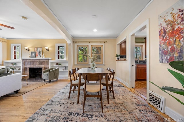 1601 Albion St, Denver, CO 80220 - dining room featuring crown molding, wood-type flooring, ceiling fan, a brick fireplace, and baseboards