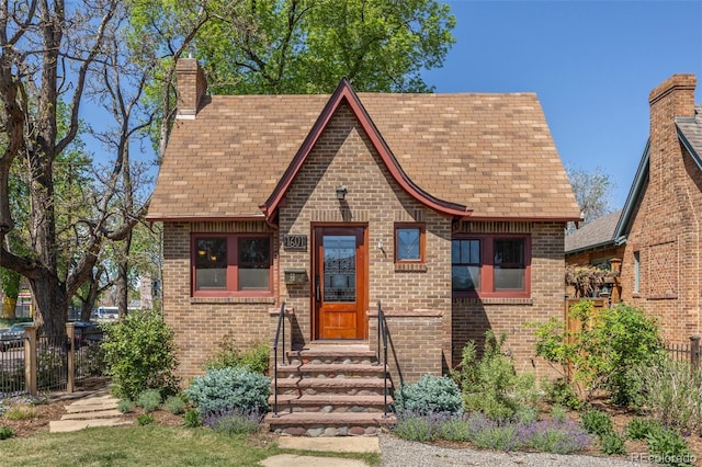 1601 Albion St, Denver, CO 80220 - tudor home featuring brick siding, fence, a chimney, roof with shingles, and entry steps