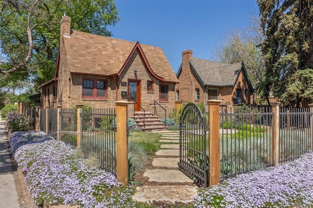 1601 Albion St, Denver, CO 80220 - tudor-style house with a chimney, brick siding, a fenced front yard, and a gate