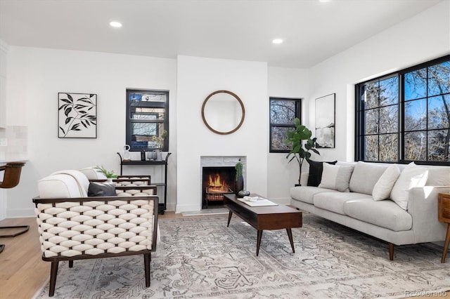 living area featuring recessed lighting, light wood-style flooring, baseboards, and a lit fireplace