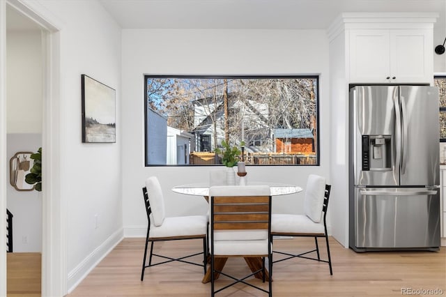 dining space with light wood-type flooring and baseboards