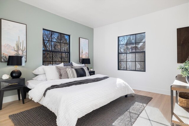 bedroom with light wood-style flooring, multiple windows, and baseboards