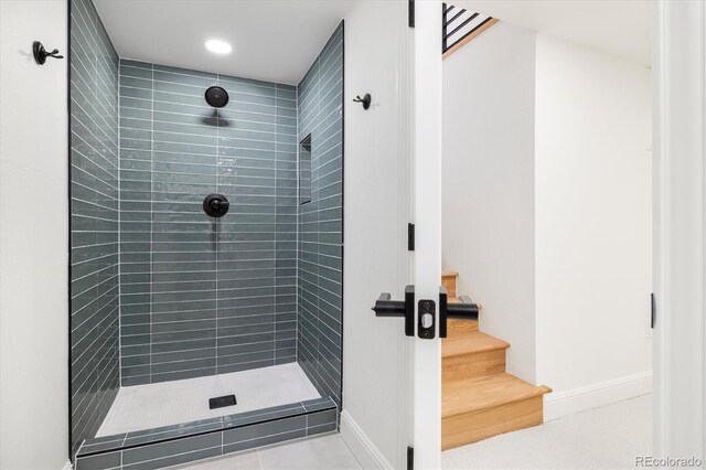 full bath with tiled shower and baseboards