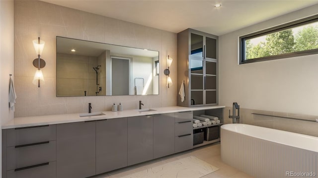 bathroom featuring tasteful backsplash, independent shower and bath, tile walls, vanity, and tile patterned floors