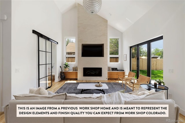 living room featuring light hardwood / wood-style floors, high vaulted ceiling, and a large fireplace