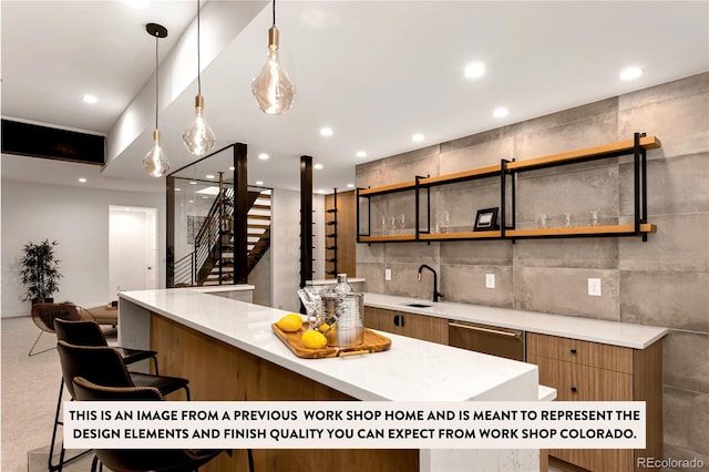 kitchen with stainless steel dishwasher, sink, a kitchen bar, and hanging light fixtures