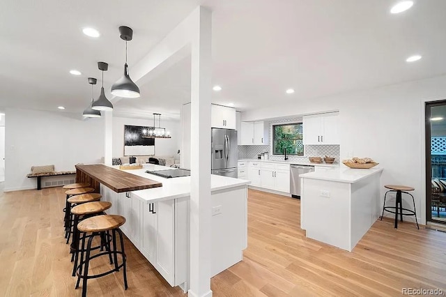 7651 Robb St, Arvada, CO 80005 - kitchen with appliances with stainless steel finishes, a kitchen bar, white cabinets, tasteful backsplash, and a peninsula