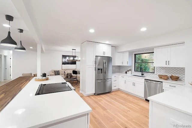 7651 Robb St, Arvada, CO 80005 - kitchen with appliances with stainless steel finishes, light wood-type flooring, tasteful backsplash, decorative light fixtures, and recessed lighting