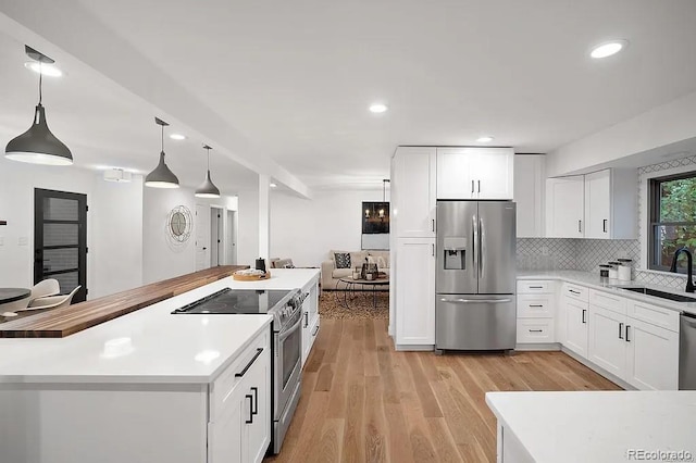 7651 Robb St, Arvada, CO 80005 - kitchen featuring appliances with stainless steel finishes, backsplash, light countertops, light wood-style floors, and white cabinetry