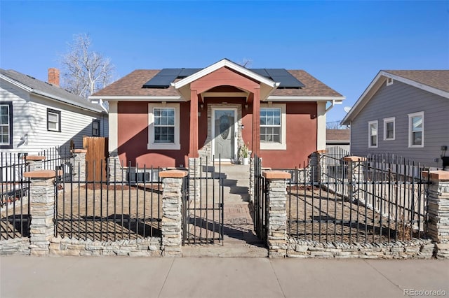 bungalow with a fenced front yard, solar panels, and stucco siding