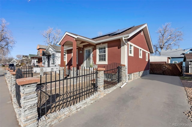 view of front of house featuring solar panels, a fenced front yard, and stucco siding