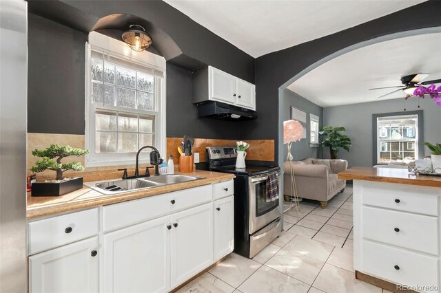 kitchen with arched walkways, open floor plan, stainless steel range with electric cooktop, under cabinet range hood, and a sink