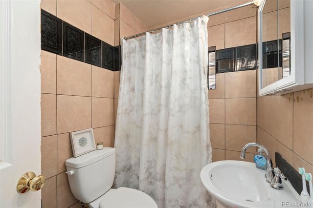 bathroom featuring a shower with shower curtain, a sink, tile walls, and toilet