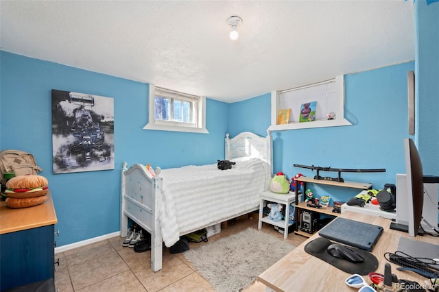 bedroom with a textured ceiling, tile patterned flooring, and baseboards