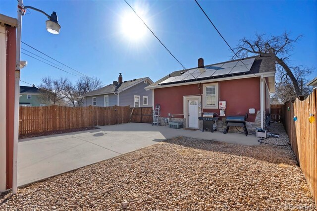 rear view of property featuring solar panels, a patio area, a fenced backyard, and stucco siding