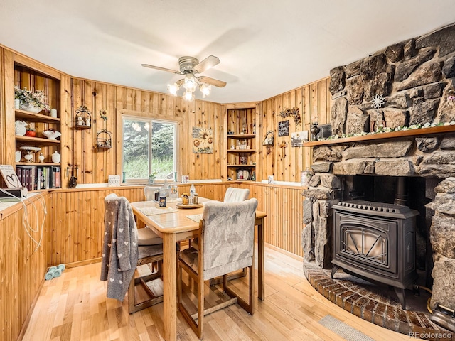 6837 S Brook Forest Rd, Evergreen, CO 80439 - dining room with wooden walls, a wood stove, ceiling fan, light wood-style floors, and built in features