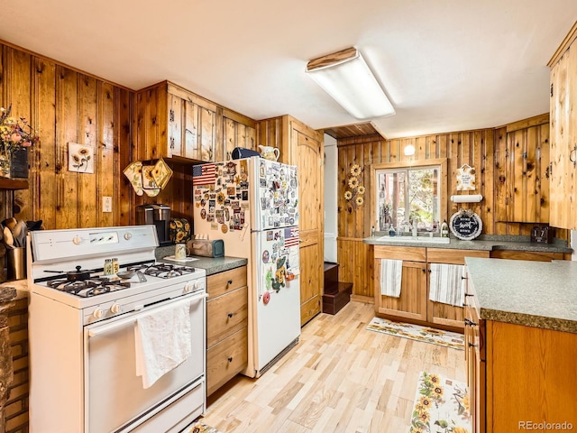 6837 S Brook Forest Rd, Evergreen, CO 80439 - kitchen with white appliances, light wood finished floors, wood walls, a sink, and brown cabinets