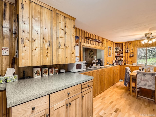 6837 S Brook Forest Rd, Evergreen, CO 80439 - kitchen featuring white microwave, wooden walls, light wood-type flooring, and a ceiling fan