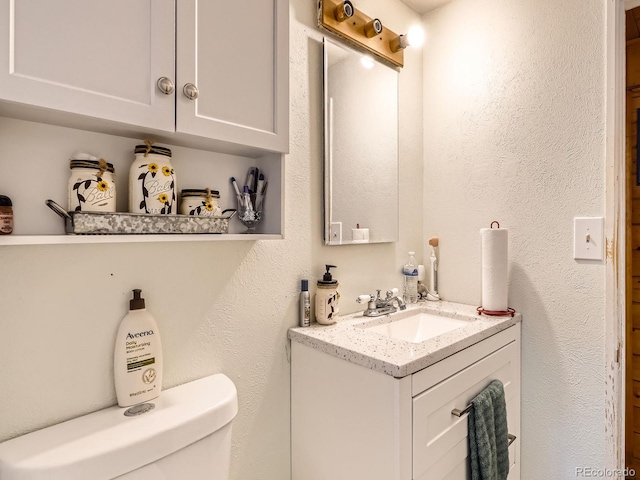 6837 S Brook Forest Rd, Evergreen, CO 80439 - bathroom with vanity, toilet, and a textured wall