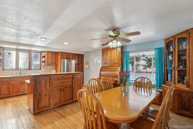 dining room with ceiling fan, a textured ceiling, and light wood-type flooring