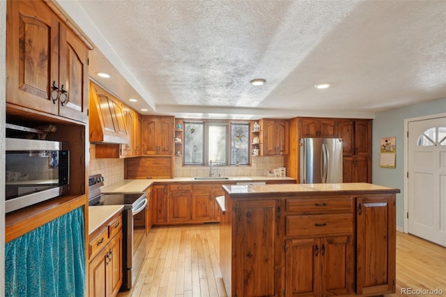 kitchen featuring stainless steel appliances, light wood-type flooring, premium range hood, open shelves, and a sink