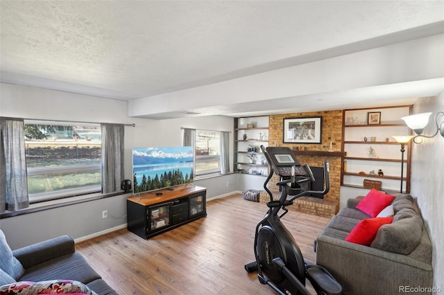 exercise area featuring a textured ceiling, wood finished floors, and baseboards