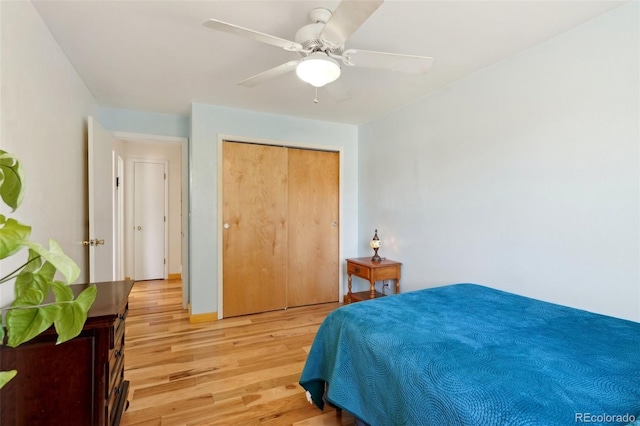 bedroom with light wood-style flooring, a ceiling fan, and a closet