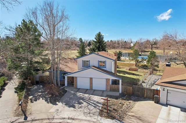 view of front of house with brick siding, driveway, an attached garage, and fence