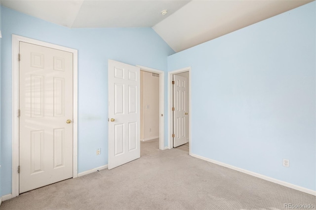 unfurnished bedroom featuring vaulted ceiling and light carpet