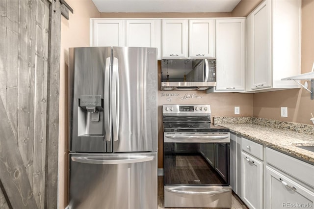 kitchen with stainless steel appliances, white cabinetry, and light stone counters