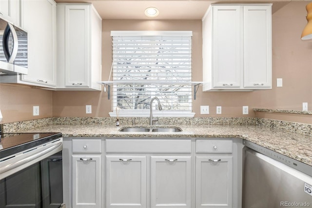 kitchen featuring stainless steel appliances, light stone countertops, sink, and white cabinets