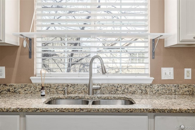 details with white cabinetry, sink, and light stone counters